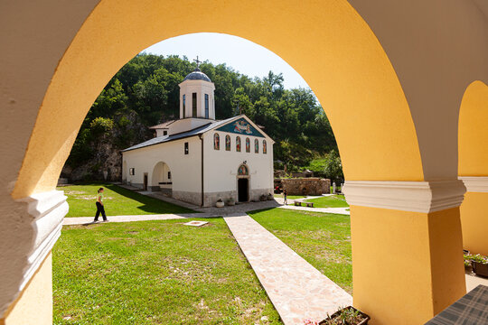 Pljevlja, Pljevlja Municipality, Montenegro - 30 July 2005: View of Holy Trinity Monastery with white walls and traditional architecture in a green courtyard, framed by a yellow arch.