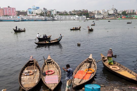 Dhaka, Bangladesh - 15 June 2026: View of Buriganga River with numerous wooden boats and workers on the water in the bustling city of Dhaka.