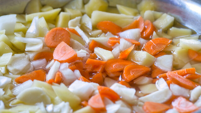 Chopped fresh vegetables carrots potatoes onion in pot for soup