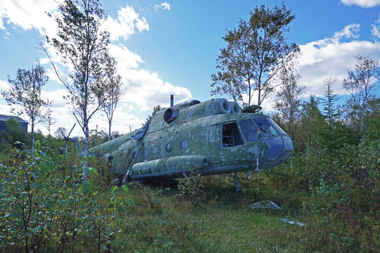 An old military helicopter.A decommissioned military helicopter stands on the grass among the trees. Abandoned aviation equipment in the open air in a natural environment.