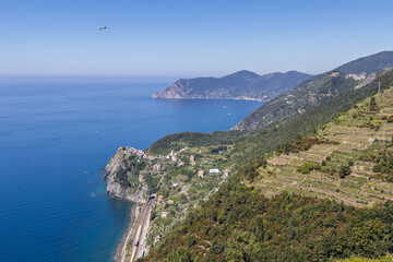 Fototapeta premium Coastal railway in Corniglia along the rugged Ligurian coast of Italy with terraced farming, seen from wide elevated trail perspective.