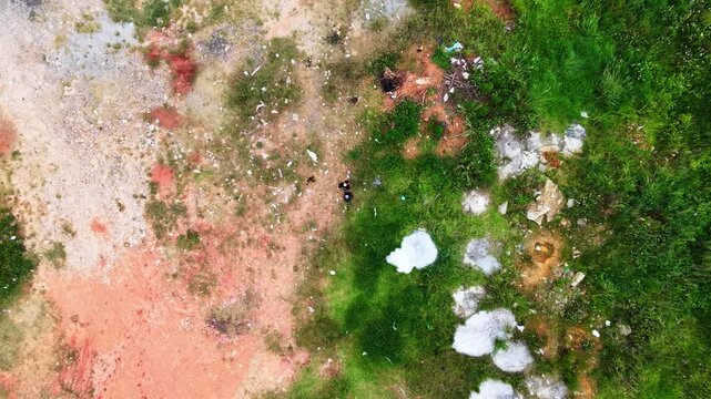 Aerial view of people walking through grassy field with patches of dirt during daytime