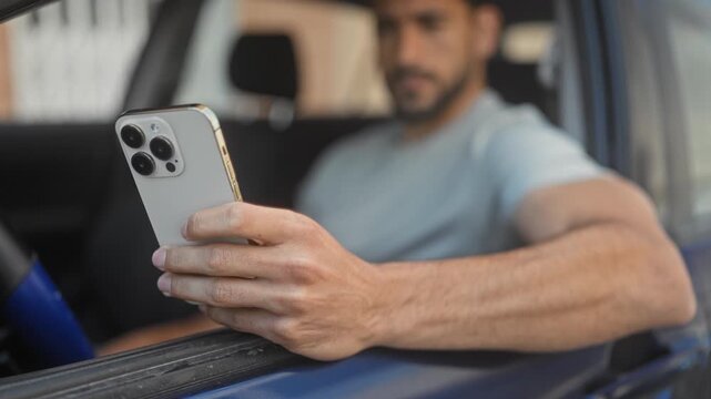 Man holding smartphone with visible hand through car window on street; concentration connectivity commute.
