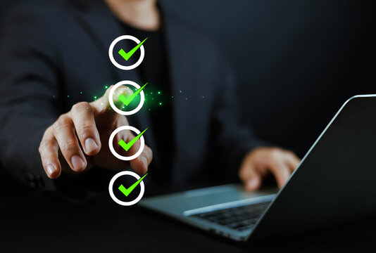 Businessman hand pointing at virtual screen with vertical checklist and green checkmark icons. Concept of task completion, project approval, digital workflow, and business efficiency.
