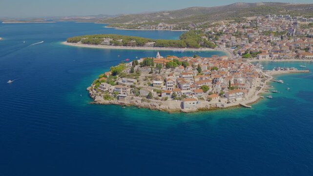 Aerial drone view of the historic town of Primo&scaron;ten in Croatia, with a smooth orbital camera movement revealing red rooftops, turquoise bays, rocky coastline, surrounding islands and the Adriatic Sea.