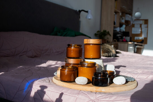 Jars with Wooden Lids on Bed. Amber Candles Glass Jars and Bottles with Natural Elements