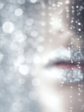 Vertical close up of lips with silver glitter makeup. Shimmering silver bokeh background with sparkling particles. Glamour beauty and festive holiday concept
