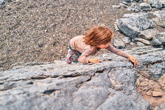 Boy climbing up a rock face seen from overhead