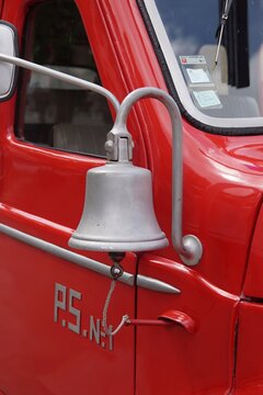 Silver bell mounted on the side of a classic red fire truck