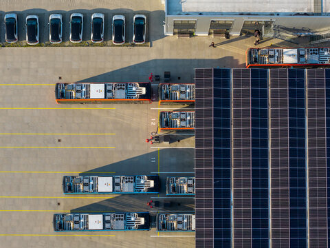 Aerial view of the EBS electric bus charging station featuring rows of parked electric buses and a large solar panel roof in Purmerend, Noord-Holland, Netherlands.