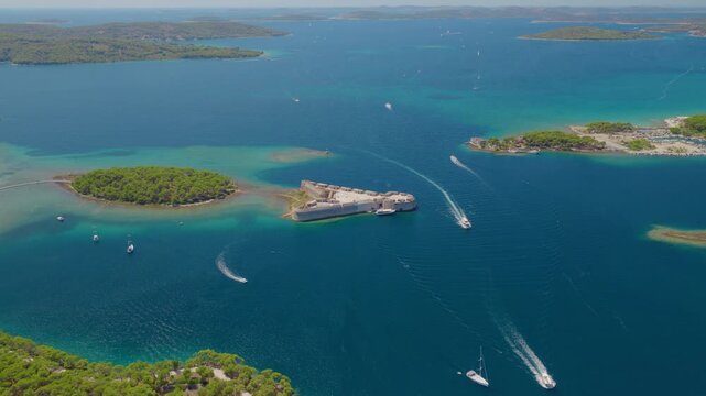 Aerial drone flight around St. Nicholas Fortress near &Scaron;ibenik, Croatia, revealing the historic stone fortification surrounded by the deep blue Adriatic Sea, boats and coastal landscape.