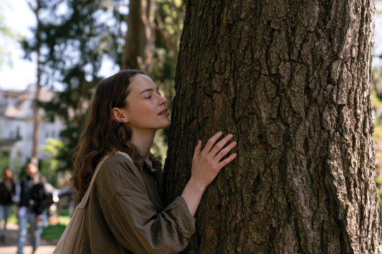 A woman gently hugs a tree in a blooming park, embodying love for nature while portraying themes of emotional connection, serenity, and the beauty of springtime.