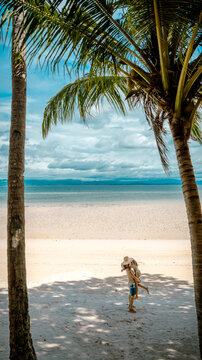 Couple lover  stay under shadow of the coconut trees at the edge of the sea beach, cheerfully traveling life in summer of the island