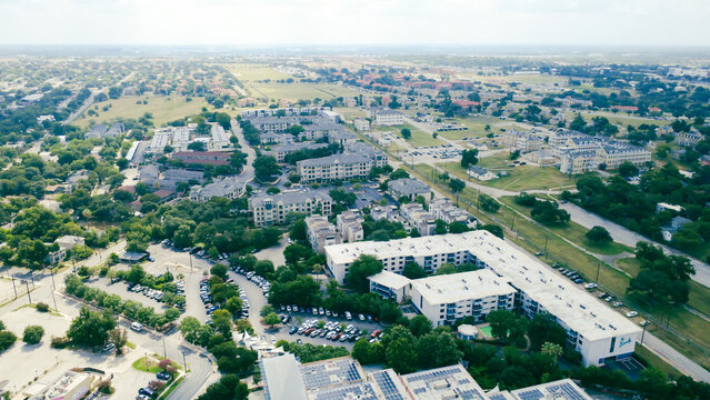 Flat roof apartment buildings flank Broadway corridor near Mahncke Park. Multi level residential units overlook spacious parking lots, open grassy fields, San Antonio, Texas