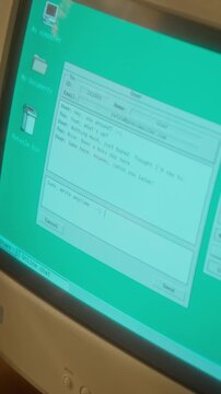 Vertical shot of retro computer monitor showing user typing message in vintage online chat application. Ideal for nostalgic technology documentaries or retro marketing campaigns