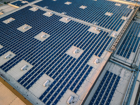 Aerial top down view of massive rooftop solar panel array on industrial warehouse, green renewable energy and ESG sustainability concept