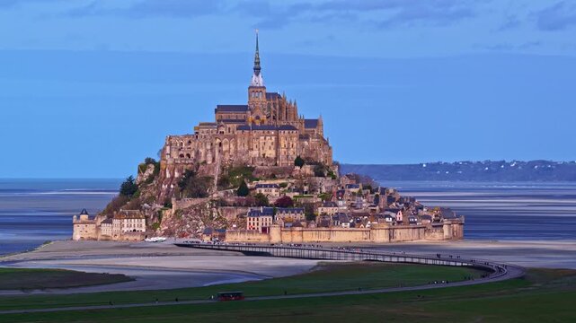 Scenic wide shot of Mont Saint Michel tidal island located in Normandy France at golden hour with soft natural light.