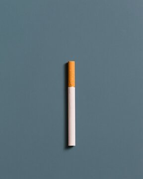 Single unbranded cigarette standing upright on a dark slate blue surface, clean and minimal packaging visual with vast copy space for a cessation campaign