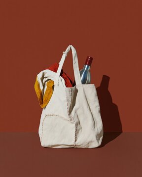 Mended cloth shopping bag with a repaired handle, featuring a folded scarf and stainless bottle, honest weathered texture for sustainable living and copy space