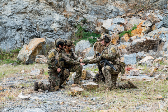 Soldiers training in a rocky area while demonstrating teamwork and coordination skills during a military exercise