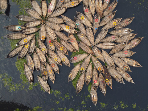 Aerial view of wooden boats arranged in a circular flower pattern on the Buriganga River in Dhaka, Bangladesh.