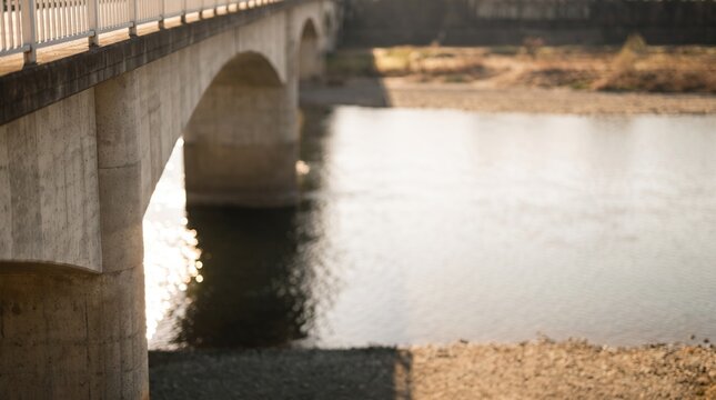 Concrete arch bridge over a shallow river on a sunny day
