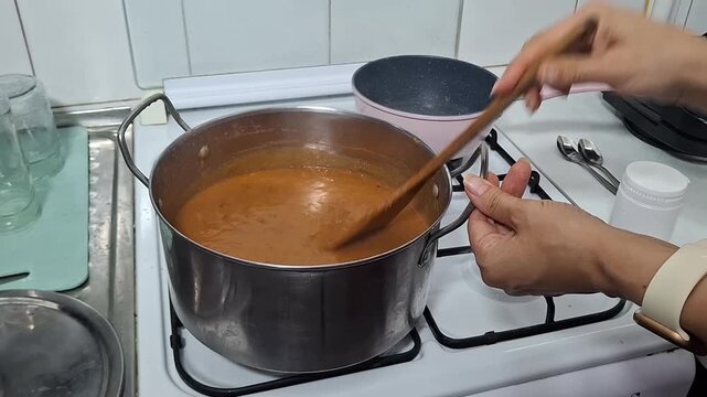 Cooking a simple dish in a kitchen with a pot on the stove and a person stirring