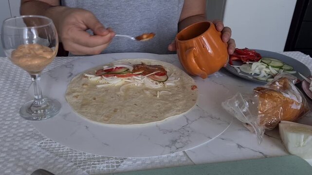 Making a tortilla wrap with chicken and vegetables in a home kitchen