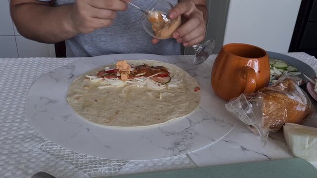 Preparing a wrap with fresh ingredients and a drink in a kitchen