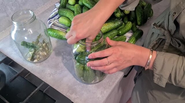 Cucumbers being packed into jars for pickling in a kitchen at home