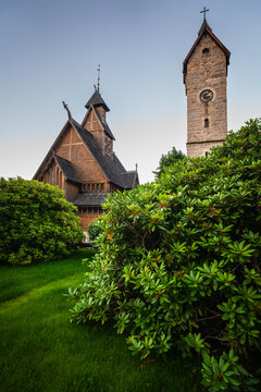 Karpacz, Poland - 29 July 2026: View of Wang Church with its distinctive wooden architecture and stone bell tower rising above lush green bushes in the foreground.