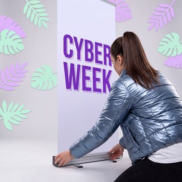 Woman assembles cyber week roll up banner in studio with tropical leaves