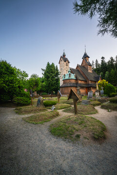 Karpacz, Lower Silesian Voivodeship, Poland - 29 July 2026: View of Wang Church with its wooden architecture, surrounded by a cemetery with old graves and trees under a clear blue sky.