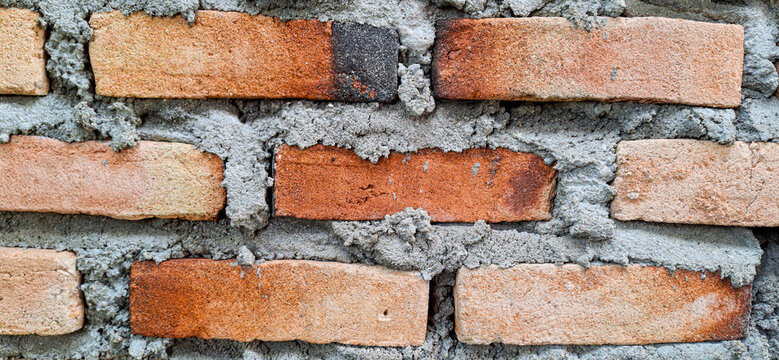 Full frame background texture of stacked red clay raw bricks, rustic construction material pattern