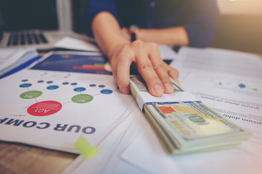 Businesswoman paid Dollars money banknotes and making decision for business investment. Selected focus	