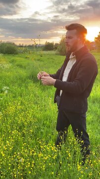 A man picking flowers in a field as the sun sets, a romantic summer bouquet, wild nature, and seasonal wildflowers