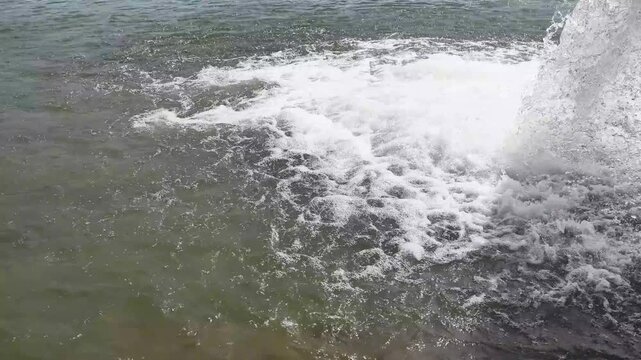 Water from a sewage drain pipe gushing into a river, creating foam and ripples on the surface. Environmental pollution concept with industrial waste discharge into the sea