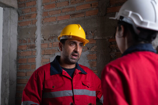 Construction engineers discussing project inspection inside an unfinished building, improving structural quality, safety compliance, teamwork, and construction management for residential development.