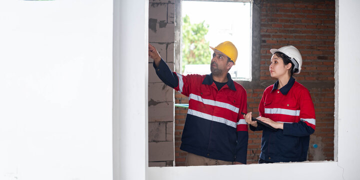 Construction engineers inspecting interior wall quality at an unfinished building, reviewing structural integrity, safety compliance, and renovation progress for professional residential construction.