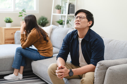 Family problem concept, Asian wife and husband sitting back to back in the living room at home have problems in a relationship and have an argument