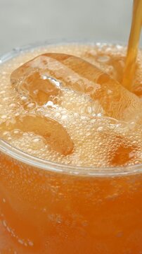 soft drink orange vertical pouring with ice cubes and bubbles,