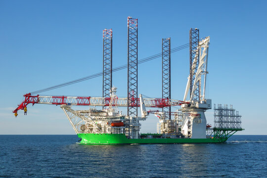Massive Green Offshore Jack-Up Installation Vessel with Heavy Lift Crane Sailing on the Sea, Concept for Renewable Energy and Marine Construction