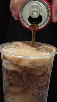Slow motion soft drink can vertical pouring with ice cubes and bubbles, 
