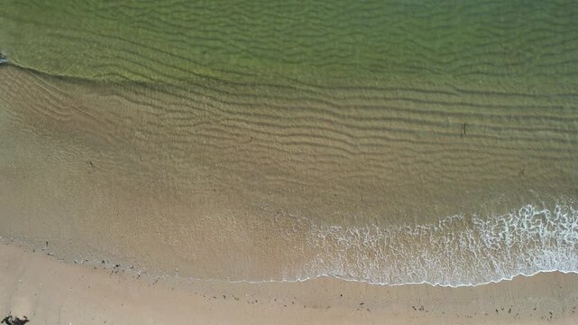 Topdown aerial of rocky sandy shoreline and shallow green water at Anse Rouge