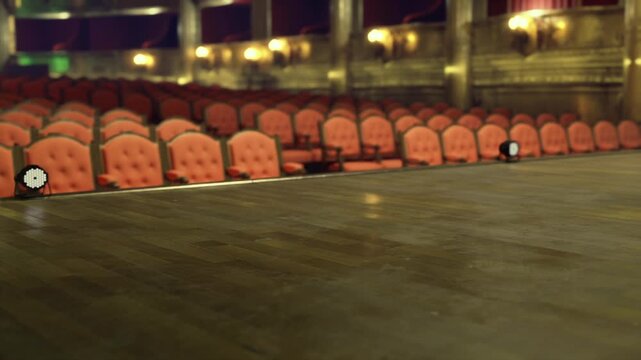 Stage edge front row seating empty, low angle reveals red plush chairs and nearest aisle, intimate proximity to performance space, warm house lights and ornate