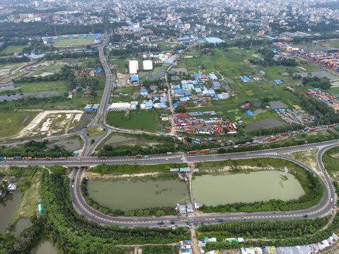 Aerial view of the Port Link Road interchange featuring highway infrastructure, ponds, industrial container yards, and urban landscape in Chittagong, Chittagong Division, Bangladesh.