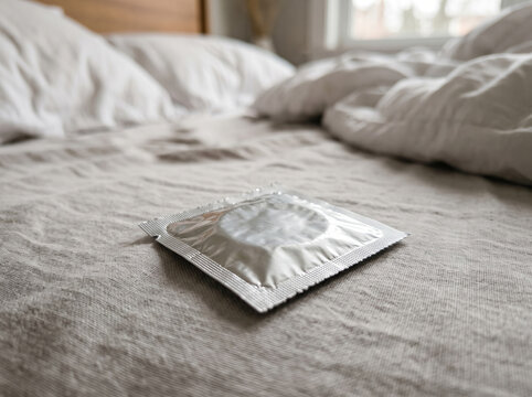 Silver Condom Packet on Unmade Cozy Bedroom Bed Linen