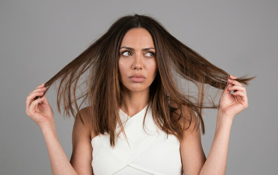 Upset woman examining split ends and damaged dry hair