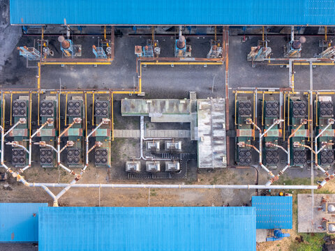 Aerial view of an industrial cooling facility with rows of fans, complex piping systems, and blue-roofed structures in Surakarta, Central Java, Indonesia.