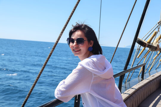 Brunette woman in sunglasses standing open deck of a cruise ship enjoying ocean views and relaxing vacation travel lifestyle.